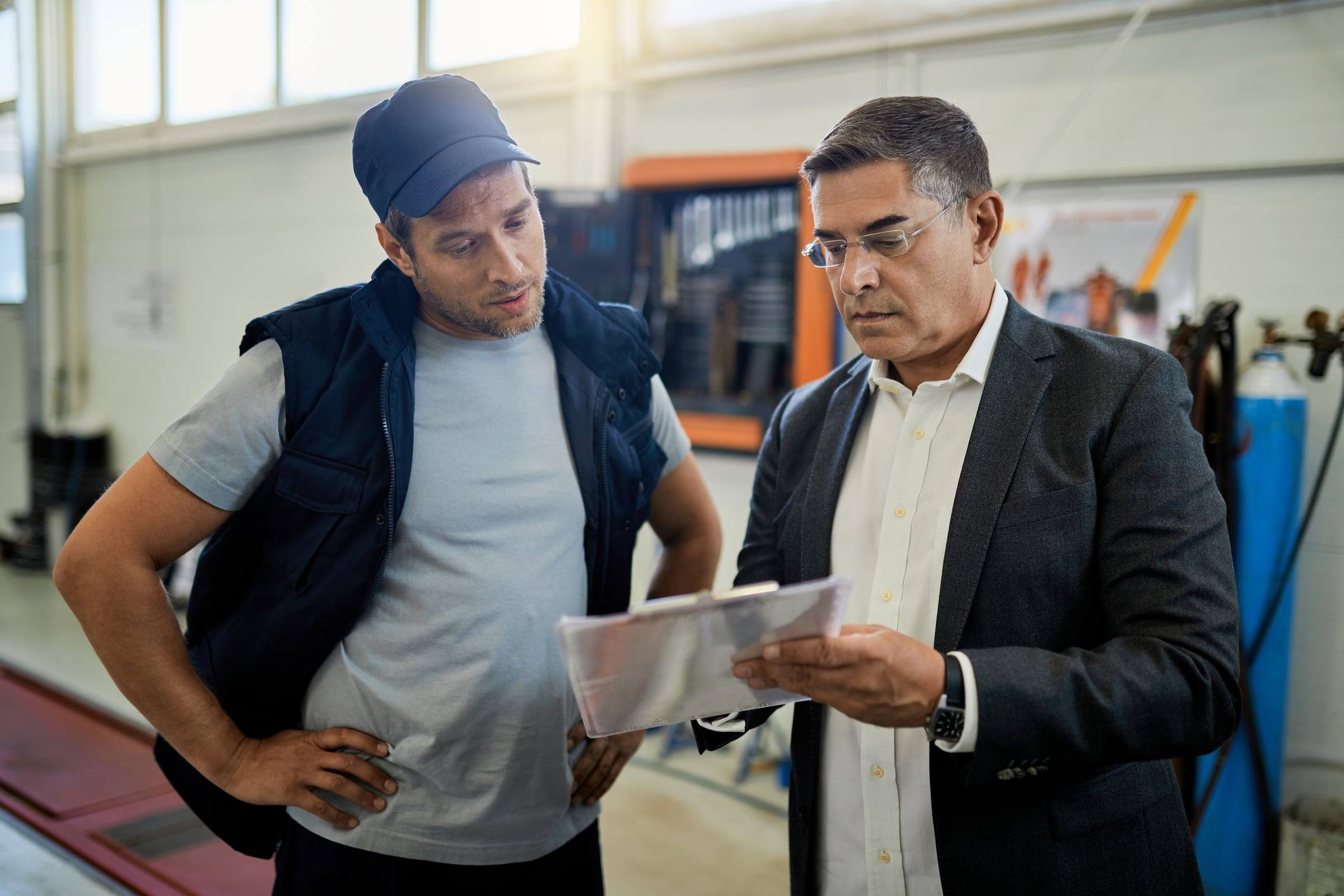 Dos colaboradores revisando un documento en planta